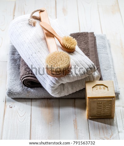 genuine extra pure Marseilles olive oil soap and dry brush to shower with simplicity, purity and respect of the environment over white wooden background, above view Royalty-Free Stock Photo #791563732