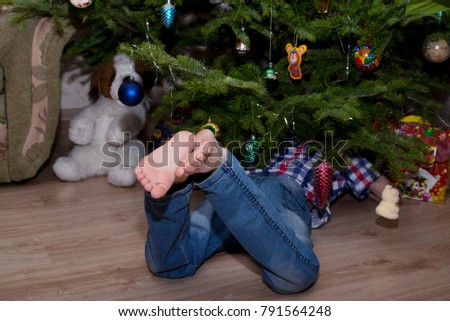 Baby feet close-up. boy is looking for a gift under a Christmas tree.
