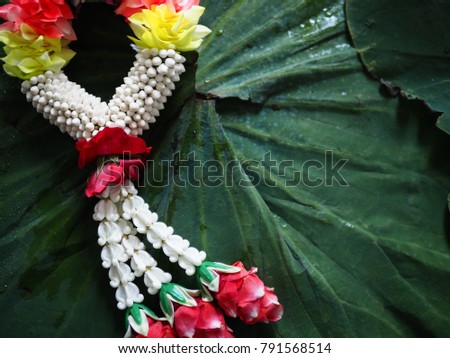 Thai traditional various colorful flowers garland on lotus pad (leaf) background. Concept image for Songkran festival, Thai new year, merit making rituals, mother's day in Thailand. (close up)