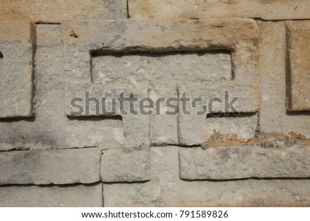 Abstract view of the facade of a brown stone wall made of bricks. Pattern composed with lines and blocks. Relief and shadow make a textured material surface. Picture taken in South of France on 2018. 