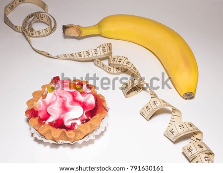 cupcake, centimeter and banana on a light background, a sweet or fruit for diet