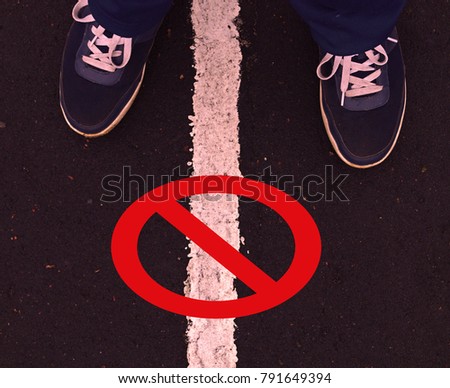Sneakers between the white line and the sign of the prohibition of red on a background of asphalt
