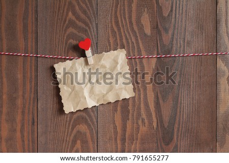 Scrap of crumpled paper with a wooden clothespeg with red heart on a rope