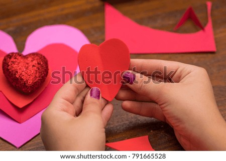 Someone holding a folded cut out heart with hearts in the background 