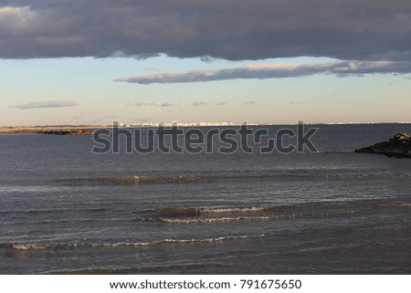 View of the beach from carnon France. At the horizon la Grande Motte city with its particular white buildings. Picture taken at the blue hour with clouds and bright colors, blue, grey, withe and brown