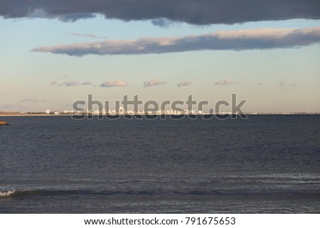 View of the beach from carnon France. At the horizon la Grande Motte city with its particular white buildings. Picture taken at the blue hour with clouds and bright colors, blue, grey, withe and brown
