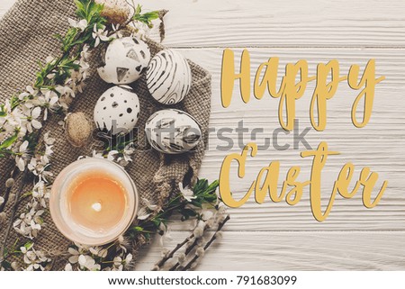 happy easter text flat lay with flowers and stylish eggs on rustic wooden background top view. modern easter greeting card. space for text