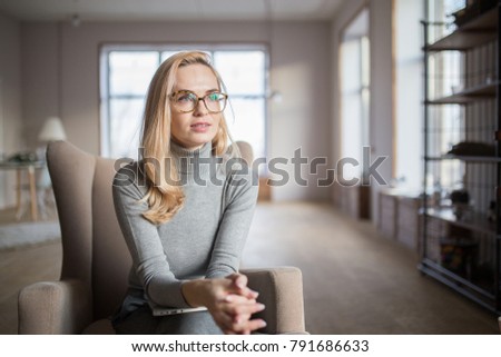 young caucasian woman with glasses sitting in a chair with a laptop on her lap