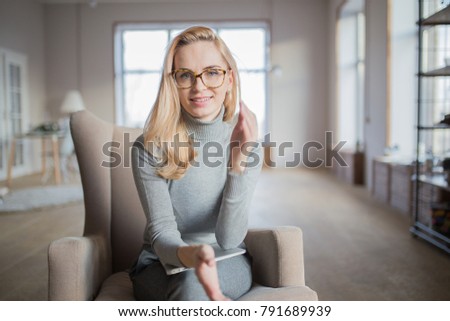 portrait of a young caucasian woman with glasses sitting in a chair with a laptop on her lap