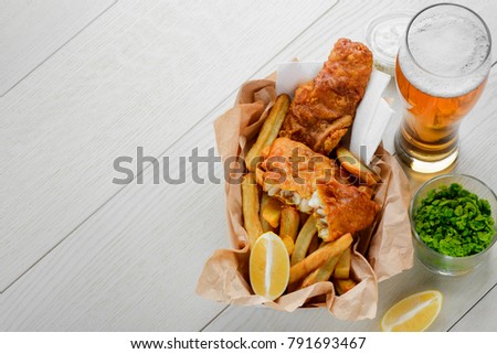 Beer to fish and fries. Addition of mashed green peas and lemon. Traditional British cuisine. Royalty-Free Stock Photo #791693467
