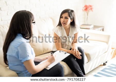 Beautiful young woman discussing her problems with female psychologist Royalty-Free Stock Photo #791708227
