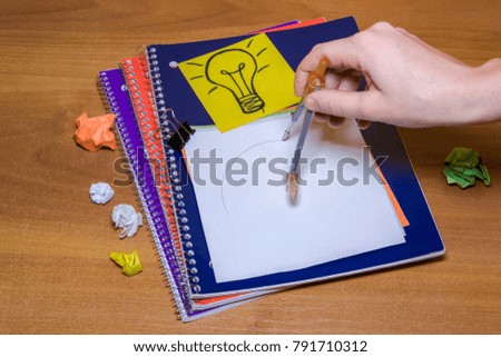 Idea concept with crumpled paper lightbulb and colored sheet with pen on wooden desktop