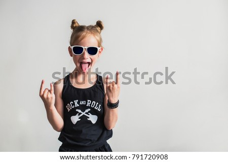 Portrait of a playful little girl with tongue out. Cute little girl making a rock-n-roll sign.