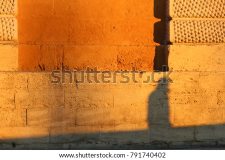 Abstract picture and pattern of shadows of people who are walking on the street in Montpellier France. Their human forms can be seen on the textured surface of an old stone wall lighted by the sun. 