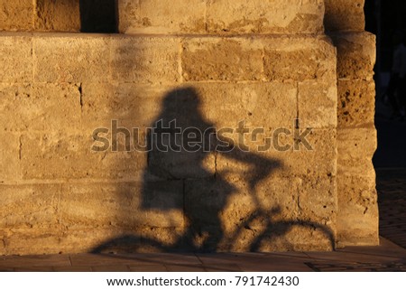 Abstract view of the shadow of a cyclist ridding his bike. The dark form can be seen on the textured surface of an old stone wall. Funny picture taken in Montpellier France on december 2017. 