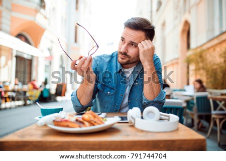 Bored handsome young man holding glasses and thinking Royalty-Free Stock Photo #791744704