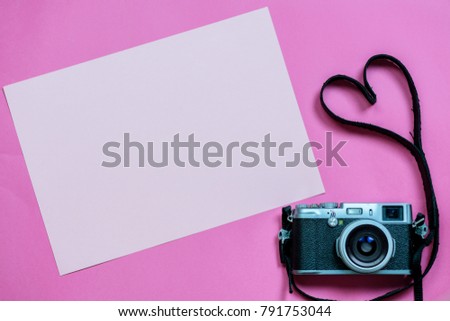 Vintage photo camera on Valentine's Day pink background with composition of blank photo frames, empty notes and hearts, top view. flat lay