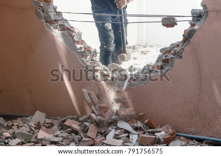 Man uses hammer smashed the walls of the house.