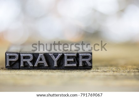 The word PRAYER concept written in vintage retro metal letterpress type on a wooden background.