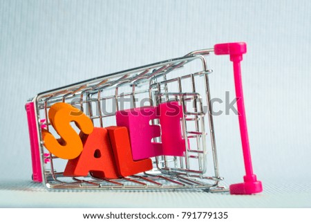 Sale colorful wooden text and shopping cart or supermarket trolley on blue background with copy space, shopping discount and marketing concept idea. template for add text or photo.
