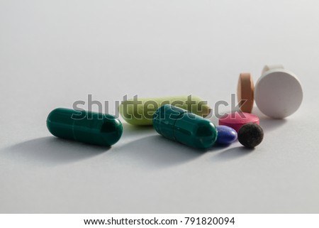 Close Up view of drug powder of antibiotics contain blue pills, yellow-red or capsules on a white background with copied clearance. Medication in healthy containers, antibiotics and dangerous drugs.