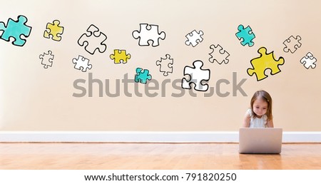 Puzzle Pieces with little girl using a laptop computer on floor