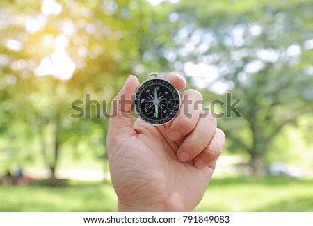 Compass in hand against nature background