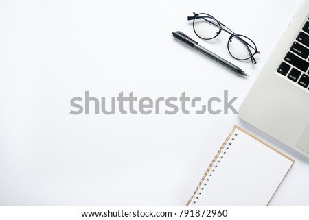 Flat lay top view of laptop, glasses, notepad & pen with copy space on white desk table. Lifestyle concept