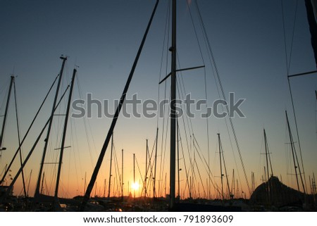 Sunset in the Marina of La grande Motte in France. View of many silhouettes of matts of boats with the sun. Geometrical design with pattern elements. Colorful vaccation picture in the summer. 