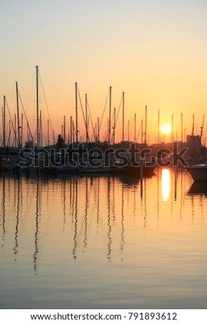 Sunset in the Marina of La grande Motte in France. View of many silhouettes of matts of boats with the sun. Geometrical design with pattern elements. Colorful vaccation picture in the summer. 