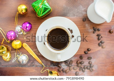 Coffee cup with beans and milk. Picture decorates with gift box and ornament for Christmas and new year holiday on he wooden floor and artificial smoke.