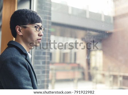 Young Asian men look out of the window in the corridor of the commercial area