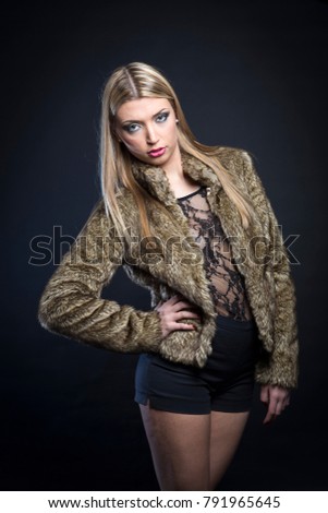 Beautiful fashion model wearing a fur coat, background s black