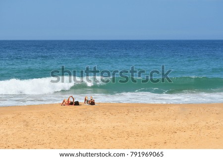 Couple on the beach with a close incoming wave