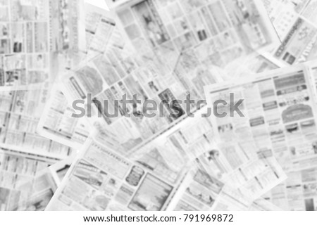 Lots of old newspapers on horizontal surface. Pages with articles, headlines and photos. Daily papers with business news. Background texture, top view, blurred