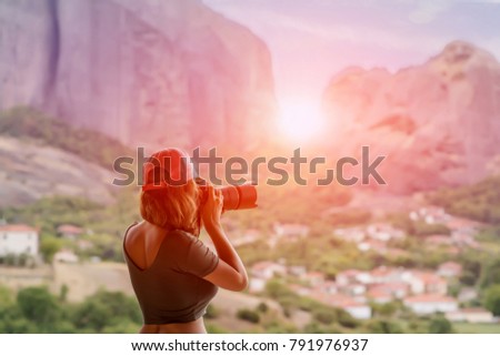 Female in red cap with camera take a picture sunset in mountain. Meteora, Greece