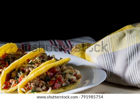 Three Mexican tacos with beef and vegetables. Mexican dish with guacamole sauces and salsa in flat cakes. With copy space.
