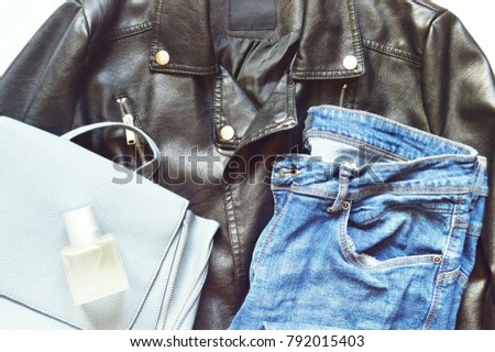 Stylish black biker jacket, blue jeans, light bag and perfume bottle. Fashion stock photo for blog. Flatlays