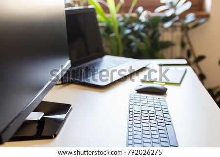 Shot of a computer, laptop computer and graphic board on an office desk during day. Off to break