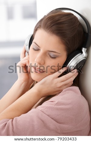 Portrait of woman daydreaming with headphone, listening to music with closed eyes.?