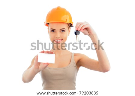 Photo of happy woman construction engineer wearing protective orange helmet holding new key and blank white card and looking at camera.