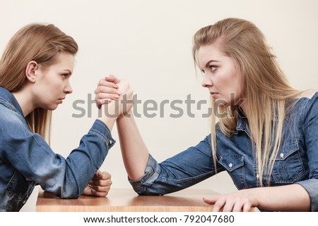 Two serious competetive women having arm wrestling fight, compete with each other.