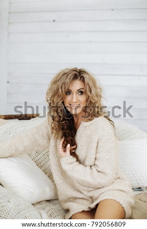 Pretty blonde and curly woman in cozy light interior