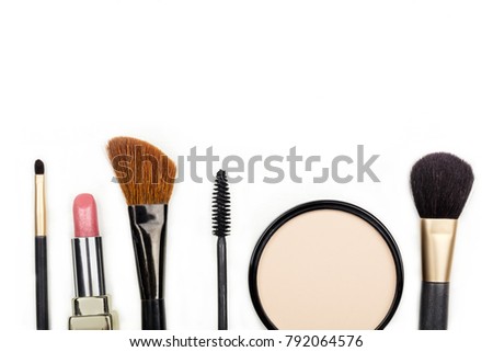 Makeup brushes, powder, lipstick, and a mascara applicator, shot from above on a white background with copy space. A template for a makeup artist's business card or flyer design