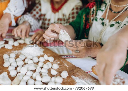 Women dressed in ethnic clothes cook varenyky