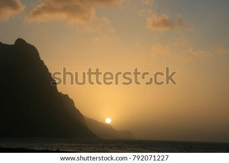 Sunset with cliffs, moutains and sea at Santa antao Island in Cape Verde. Silhouettes of the mountains in a purple colored design in the evening. A peaceful panoramic picture during the holidays.