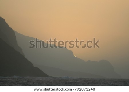 Sunset with cliffs, moutains and sea at Santa antao Island in Cape Verde. Silhouettes of the mountains in a purple colored design in the evening. A peaceful panoramic picture during the holidays.