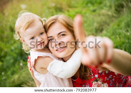 Mother and her adorable daughter playing, kissing and hugging in green field. Concept of love and happy family. Happy mother's day