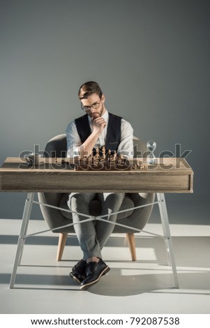 thoughtful young businessman in eyeglasses playing chess