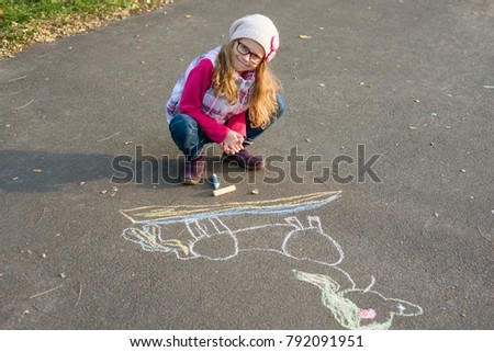Drawings on the sidewalk, girl child draws a unicorn